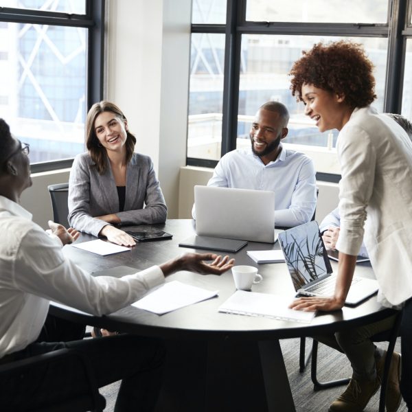 Millennial black businesswoman stands listening to corporate colleagues at a meeting, close up