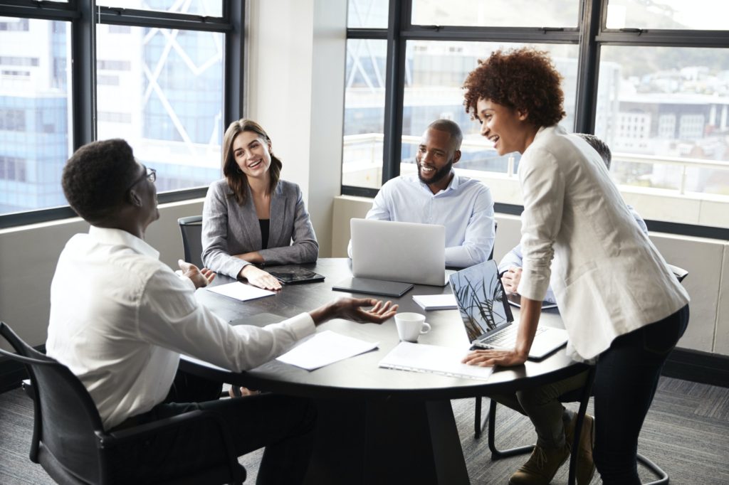 Millennial black businesswoman stands listening to corporate colleagues at a meeting, close up